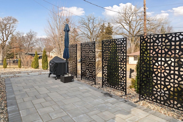 view of patio featuring fence, a gate, and a grill