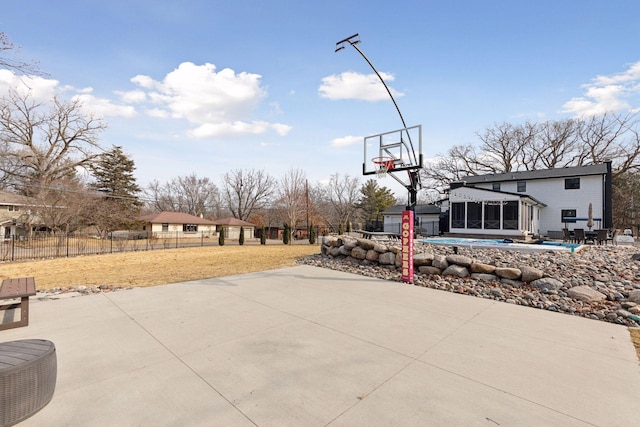 view of sport court featuring basketball hoop, fence, and a lawn