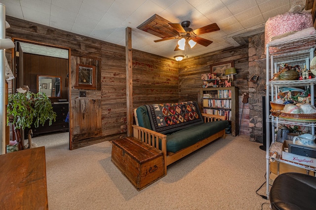 living area featuring carpet, wood walls, and ceiling fan