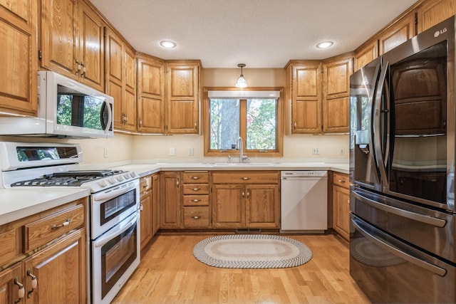 kitchen with sink, black refrigerator, double oven range, dishwasher, and pendant lighting