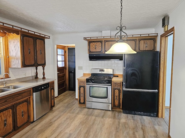 kitchen with sink, hanging light fixtures, light wood-type flooring, stainless steel appliances, and backsplash