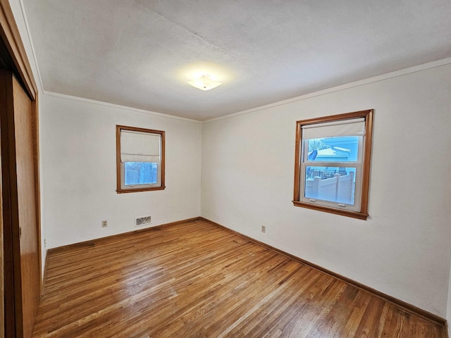 unfurnished room featuring hardwood / wood-style flooring, crown molding, and a wealth of natural light