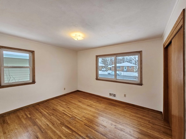 unfurnished bedroom with hardwood / wood-style flooring, crown molding, and a closet