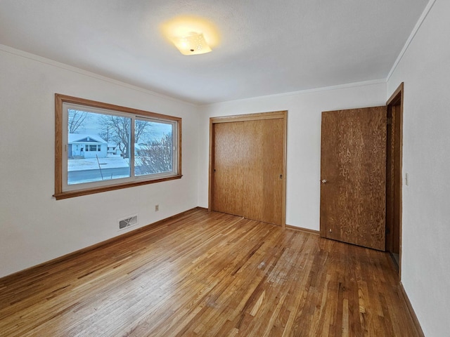 unfurnished bedroom with ornamental molding, wood-type flooring, and a closet