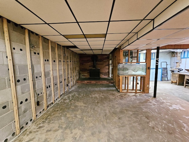 basement featuring a wood stove and a drop ceiling