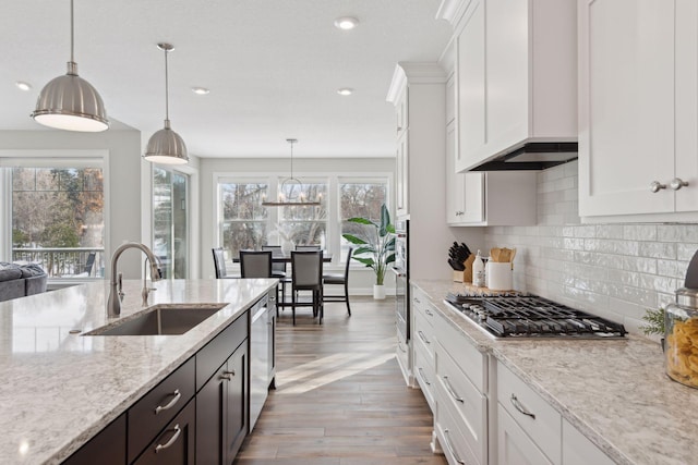 kitchen featuring sink, appliances with stainless steel finishes, white cabinetry, light stone counters, and decorative light fixtures