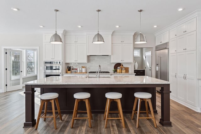 kitchen with pendant lighting, white cabinetry, and an island with sink