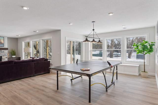 playroom featuring a fireplace, light hardwood / wood-style floors, and a textured ceiling