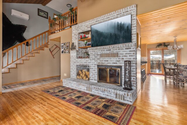 1378 Larrup Trl SW, Pine River, MN 56474 - unfurnished living room featuring a wall mounted air conditioner, wood finished floors, a chandelier, stairs, and a brick fireplace