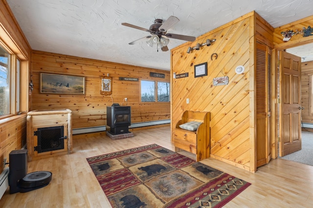 1378 Larrup Trl SW, Pine River, MN 56474 - living room with a wood stove, baseboard heating, a baseboard heating unit, wood finished floors, and wooden walls