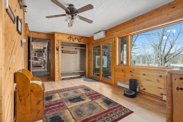 1378 Larrup Trl SW, Pine River, MN 56474 - sitting room with wooden walls, wood finished floors, a ceiling fan, a wall mounted air conditioner, and a baseboard radiator