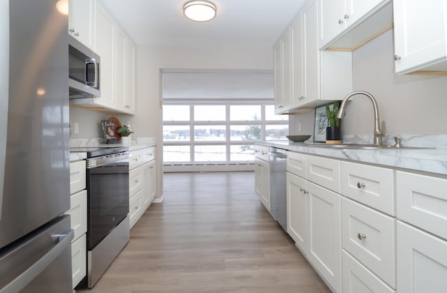 kitchen featuring sink, light stone counters, stainless steel appliances, light hardwood / wood-style floors, and white cabinets