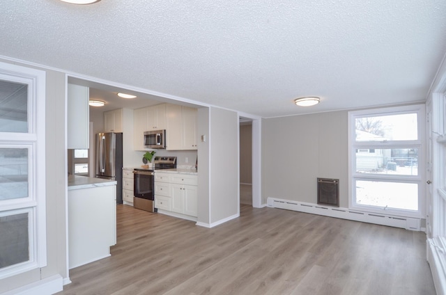 kitchen featuring appliances with stainless steel finishes, white cabinets, baseboard heating, a textured ceiling, and light hardwood / wood-style flooring