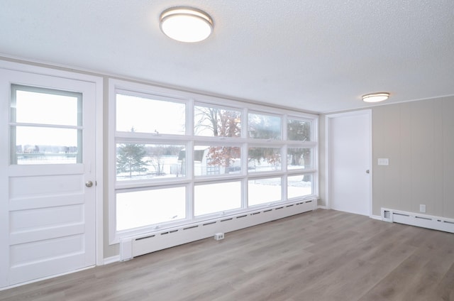 unfurnished room featuring a baseboard radiator, light hardwood / wood-style floors, and a textured ceiling