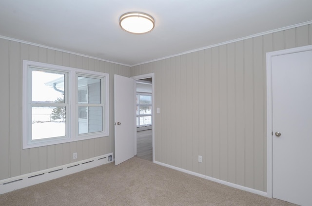 unfurnished room with crown molding, a baseboard heating unit, and light carpet