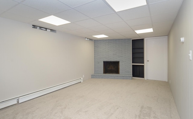 unfurnished living room with baseboard heating, carpet floors, a brick fireplace, and a drop ceiling