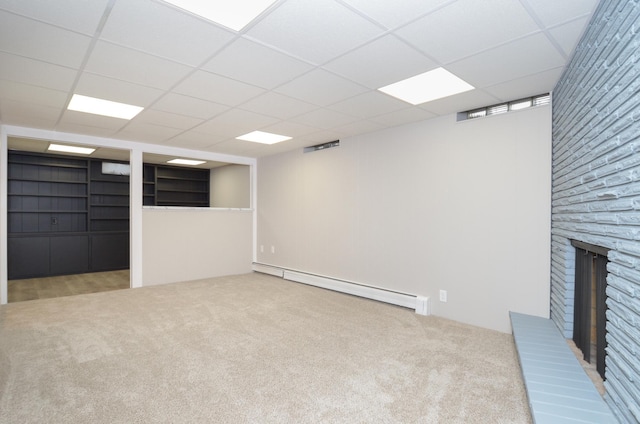 basement featuring a drop ceiling, a fireplace, carpet floors, and a baseboard heating unit