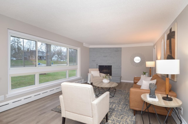 living room with a fireplace, wood finished floors, baseboard heating, and baseboards
