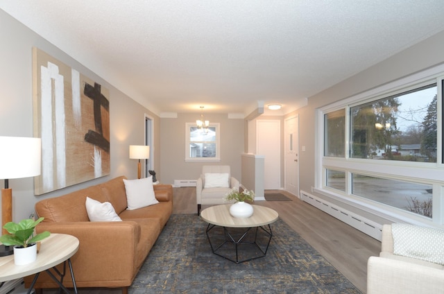 living room with baseboard heating, wood finished floors, a notable chandelier, and a baseboard heating unit