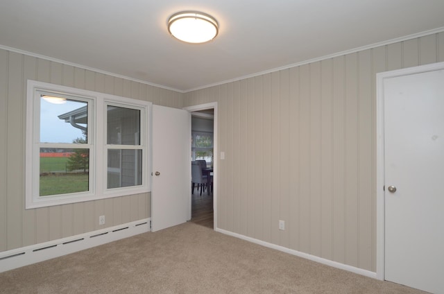 unfurnished room featuring crown molding, baseboard heating, and carpet floors