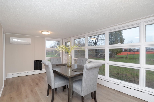 dining area featuring baseboard heating, light wood-type flooring, a wall unit AC, and a textured ceiling