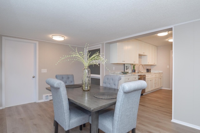 dining area featuring a textured ceiling, baseboards, and light wood-style floors