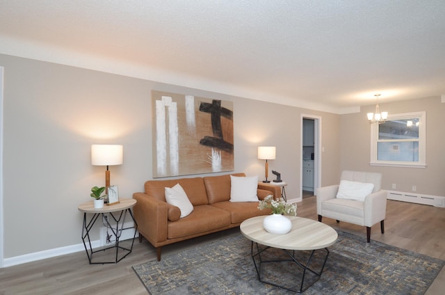 living area with an inviting chandelier, a baseboard radiator, wood finished floors, and baseboards