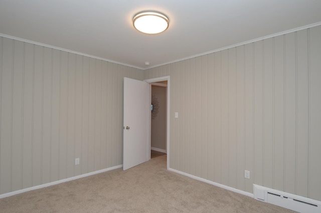 spare room with light colored carpet, crown molding, and a baseboard heating unit