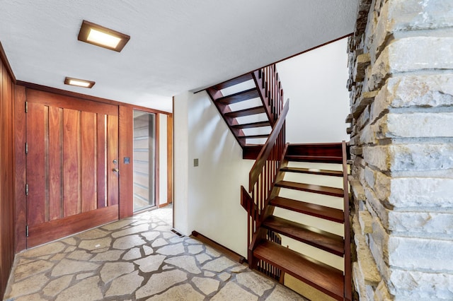 carpeted foyer with stairs and a textured ceiling