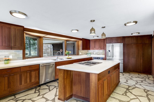 kitchen featuring tasteful backsplash, appliances with stainless steel finishes, hanging light fixtures, light countertops, and a sink