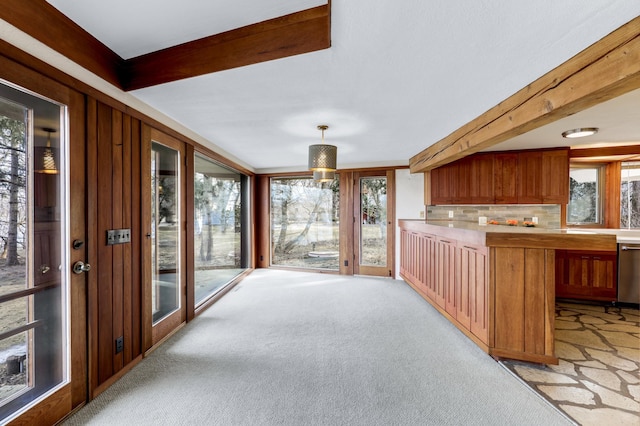 interior space featuring light colored carpet, light countertops, beam ceiling, dishwasher, and brown cabinetry