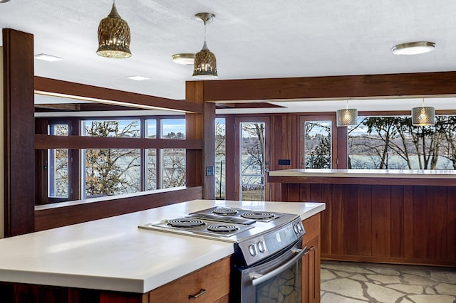 kitchen with stainless steel range with electric stovetop, beam ceiling, light countertops, and stone finish flooring