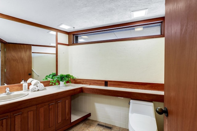 bathroom with visible vents, toilet, a textured ceiling, and vanity