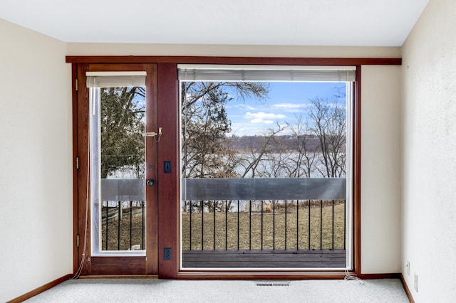 doorway to outside featuring carpet floors, visible vents, and baseboards