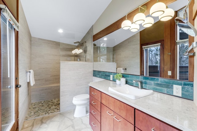 bathroom with lofted ceiling, toilet, vanity, tile walls, and walk in shower