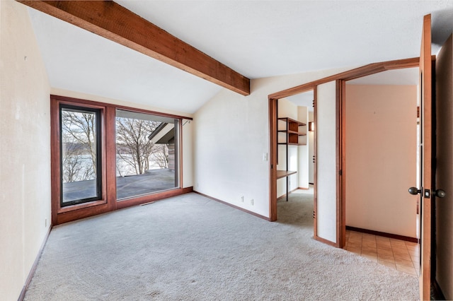 carpeted spare room with lofted ceiling with beams and baseboards