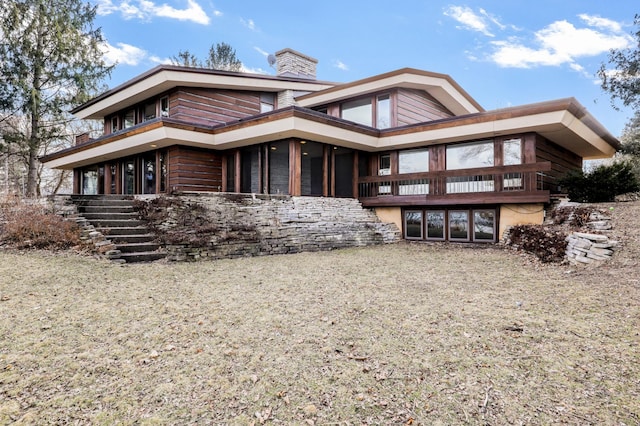 view of front of home featuring stairway, a chimney, and a balcony