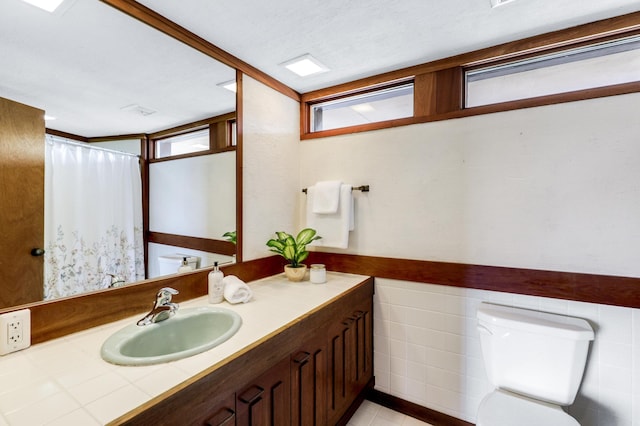 full bath featuring wainscoting, toilet, curtained shower, vanity, and tile walls