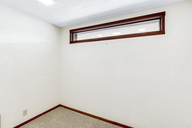 interior space featuring a textured ceiling, carpet flooring, and baseboards