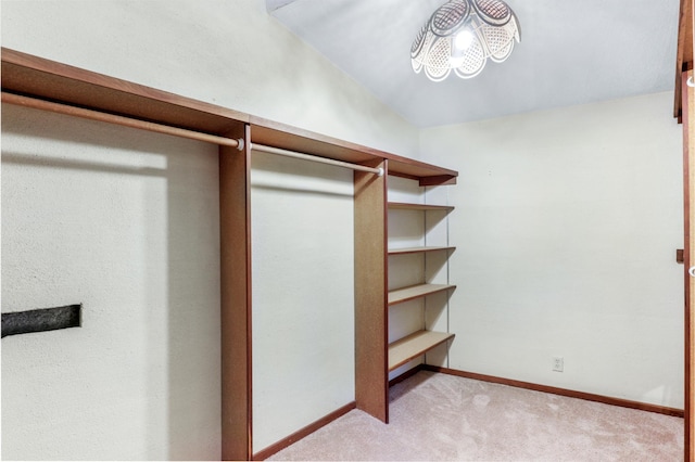 walk in closet with light carpet and vaulted ceiling