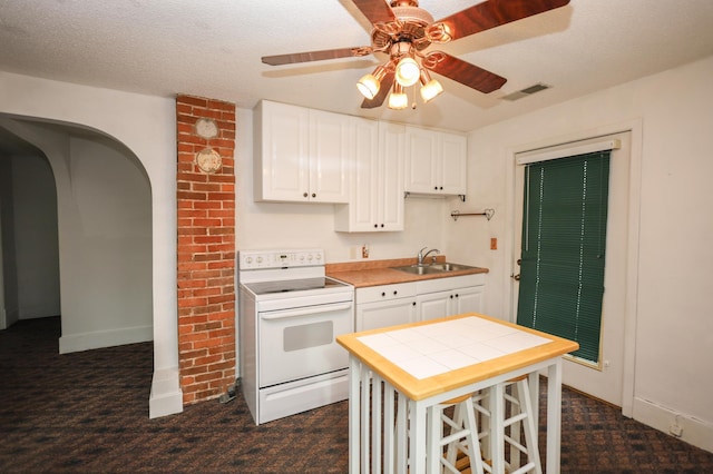 kitchen featuring white electric range, sink, a textured ceiling, a kitchen breakfast bar, and white cabinets