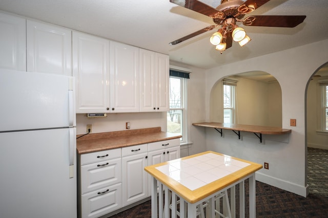 kitchen featuring white fridge, tile counters, white cabinets, and kitchen peninsula