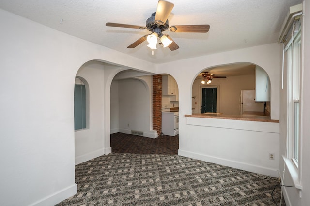 carpeted empty room featuring ceiling fan and a textured ceiling