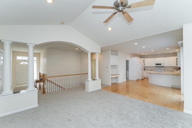 carpeted empty room with ceiling fan, decorative columns, and lofted ceiling