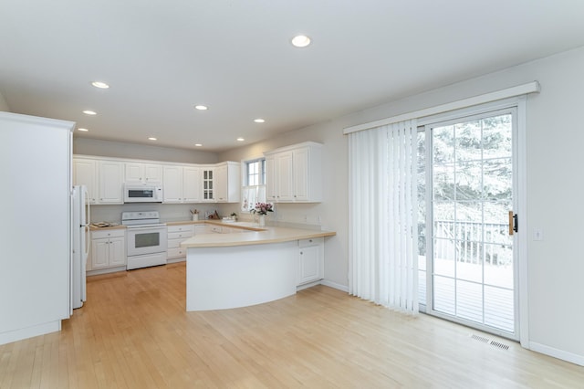 kitchen with kitchen peninsula, white appliances, white cabinets, and light hardwood / wood-style floors