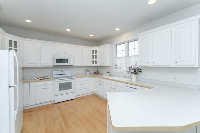 kitchen with white cabinetry, kitchen peninsula, light wood-type flooring, sink, and white appliances