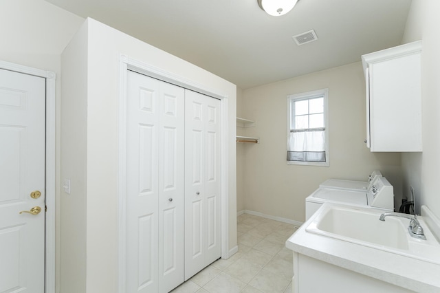 clothes washing area with light tile patterned flooring, cabinets, washing machine and dryer, and sink