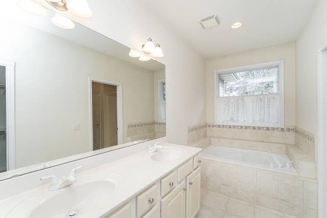 bathroom featuring tile patterned floors, vanity, and a relaxing tiled tub