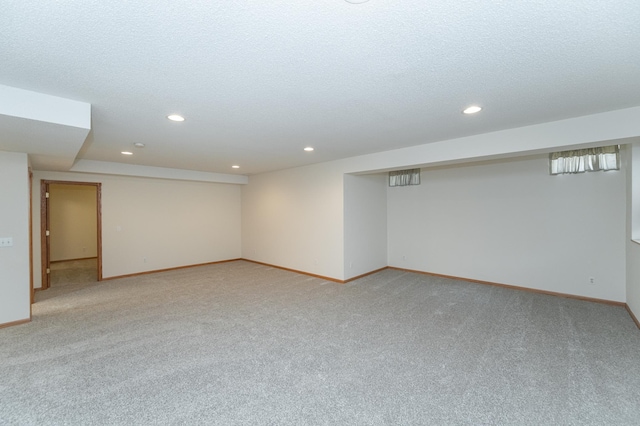 basement featuring a textured ceiling and light colored carpet