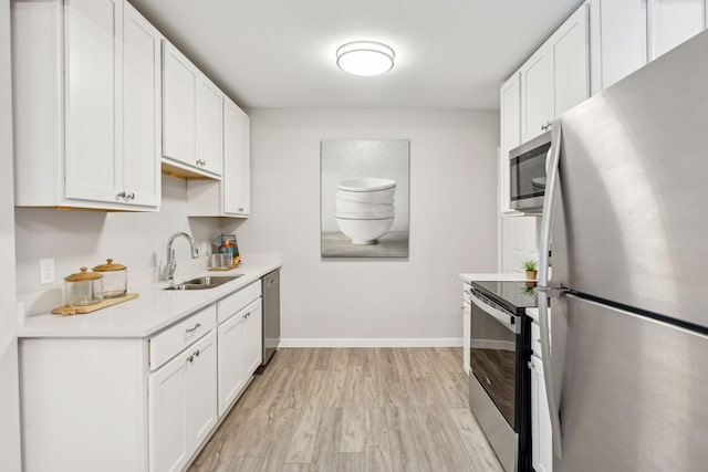 kitchen featuring white cabinetry, appliances with stainless steel finishes, sink, and light hardwood / wood-style floors